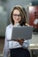 Portrait of a solid businesswoman holding laptop , controlling work process in a airplane manufactory.