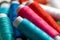 A portrait of some spools of colorful thread lying on some other rolls of fiber. The yarn or wire is ready to be used for a sewing