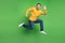 Portrait of sporty energetic guy jump run wave hand say hello on green background