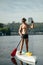 Portrait of sporty handsome man with sexy body rowing at sea standing on sup board. Vertical. Active summer vacation