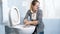 Portrait of squeamish young woman cleaning toilet with brush