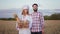 Portrait of a standing farmer man and woman baker with a basket full of fresh bread in the middle of the wheat field