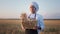 Portrait of a standing in front of the camera mature man baker holding a basket with bread in the middle of wheat field