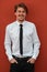 Portrait of startup businessman in a white shirt with a black tie standing in front of red wall outside