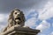 Portrait of a stone lion from the Chain Bridge across the river Danube, Budapest. Blue sky with clouds