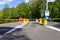 A portrait of a street closed by a barrier bar with some traffic signs in front of them. The automatic gate system provides some