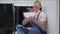 Portrait of stressed Caucasian repairman in uniform looking up at leaking ceiling as water falling in bowl in hands