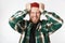 Portrait of stressed man wearing hat and plaid shirt screaming and grabbing head, while standing isolated over white background