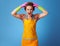 Portrait of stressed modern woman in yellow apron on blue