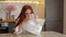 Portrait of stressed young woman playing pops transparent bubble wrap to calm herself sitting at table in kitchen room.