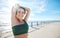 Portrait, stretching and happy fitness by woman at beach for running, exercise or cardio on blue sky background. Face