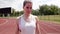 Portrait of a strong and fit Caucasian woman athlete looking into the camera. Athlete stands at running stadium on