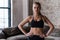 Portrait of strong slim sporty Caucasian young sportswoman wearing black sports bra standing with hands on hips looking