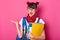 Portrait of student with two bunches, wears t shirt, overalls, bandana, holds paper folder, takes palm aside, has astonished