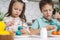 Portrait of studiously joyful two kids boy and girl, painting brush coloring Easter eggs. Traditional event. Close up