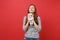 Portrait of stunning young woman in casual striped clothes holding teddy bear plush toy in hands isolated on bright red