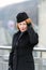 Portrait of styled woman in black coat. Red hair lady in coat, hat and gloves. Woman`s serious look at you.