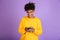 Portrait of stylish american guy smiling and holding smartphone, isolated over violet background