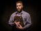 Portrait of stylish barber with beard and professional tools on a dark background.