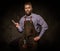 Portrait of stylish barber with beard and professional tools on a dark background.