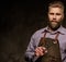 Portrait of stylish barber with beard and professional tools on a dark background.