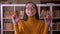 Portrait of stylish brunette female teacher praying with crossed-fingers hoping for luck at the library.