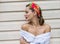 Portrait of stylish brunette girl with red lips dressed in white shirt with naked shoulder  over wall