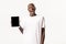 Portrait of stylish excited african-american blond guy in glasses, showing digital tablet screen, looking surprised and