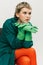 Portrait of stylish extravagant girl in bright green and orange outfit posing isolated over grey studio background
