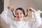 Portrait of stylish foolish attractive smiling preteen girl holding up her pigtails and making faces sitting on sofa at home. Havi