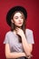 Portrait stylish girl wearing black hat isolated over red background