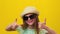 portrait of stylish little children girl with sunglasses and hat gesturing thumbs up