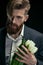 Portrait of stylish man in suit holding tulips on black, mother\'s day holiday concept