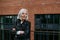 Portrait of stylish mature woman with gray hair on city street. Older woman in leather jacket with soft smile.