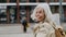 Portrait of stylish mature woman with gray hair on city street. Stunning woman crossing a road on pedestrian crossing