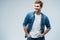 Portrait of stylish, stunning man in denim outfit standing over grey background.