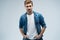 Portrait of stylish, stunning man in denim outfit standing over grey background.