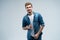 Portrait of stylish, stunning man in denim outfit standing over grey background.