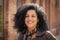 Portrait of stylish young African American woman smiling and looking at camera. Brunette with curly hair in brown