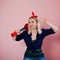 Portrait of stylish young blonde with ukulele. A woman with a headband on a pink background