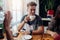 Portrait of stylish young guy holding a cup of tea having breakfast with friends in cafe