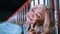 Portrait of a stylish young woman with blonde hair and colorful makeup posing by a red railing