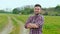 Portrait of successful agronomist man looking to camera in the green wheat field