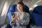 portrait of A successful asian business woman in a plane sits in a business class seat and uses a smartphone for playing