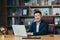 Portrait of a successful Asian businessman, man working in the office sitting at the table, looking at the camera and smiling,