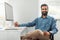 Portrait of successful bearded indian male entrepreneur sitting at workplace in front of computer in office