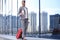 Portrait of successful business woman traveling with case at airport. Beautiful stylish female travel with luggage