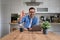 Portrait of successful businessman showing OK sign while working over laptop on desk at home