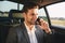 Portrait of successful director man in suit talking on smartphone, while back sitting in business class car