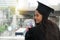 Portrait of successful graduate female student wearing cap and g